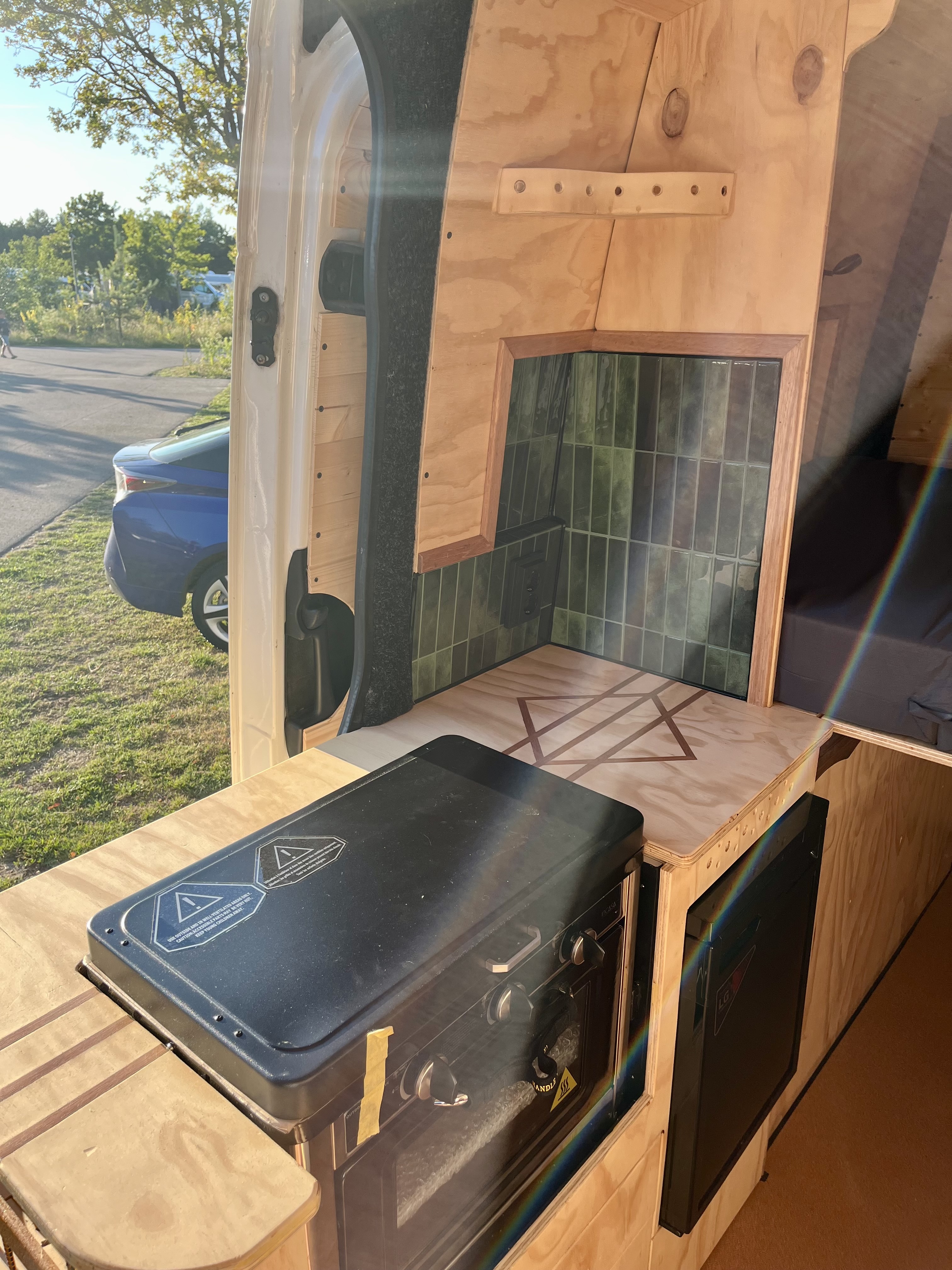 Keuken met gasstel, oven en groene keramische tegels, gezien vanuit de achterdeur