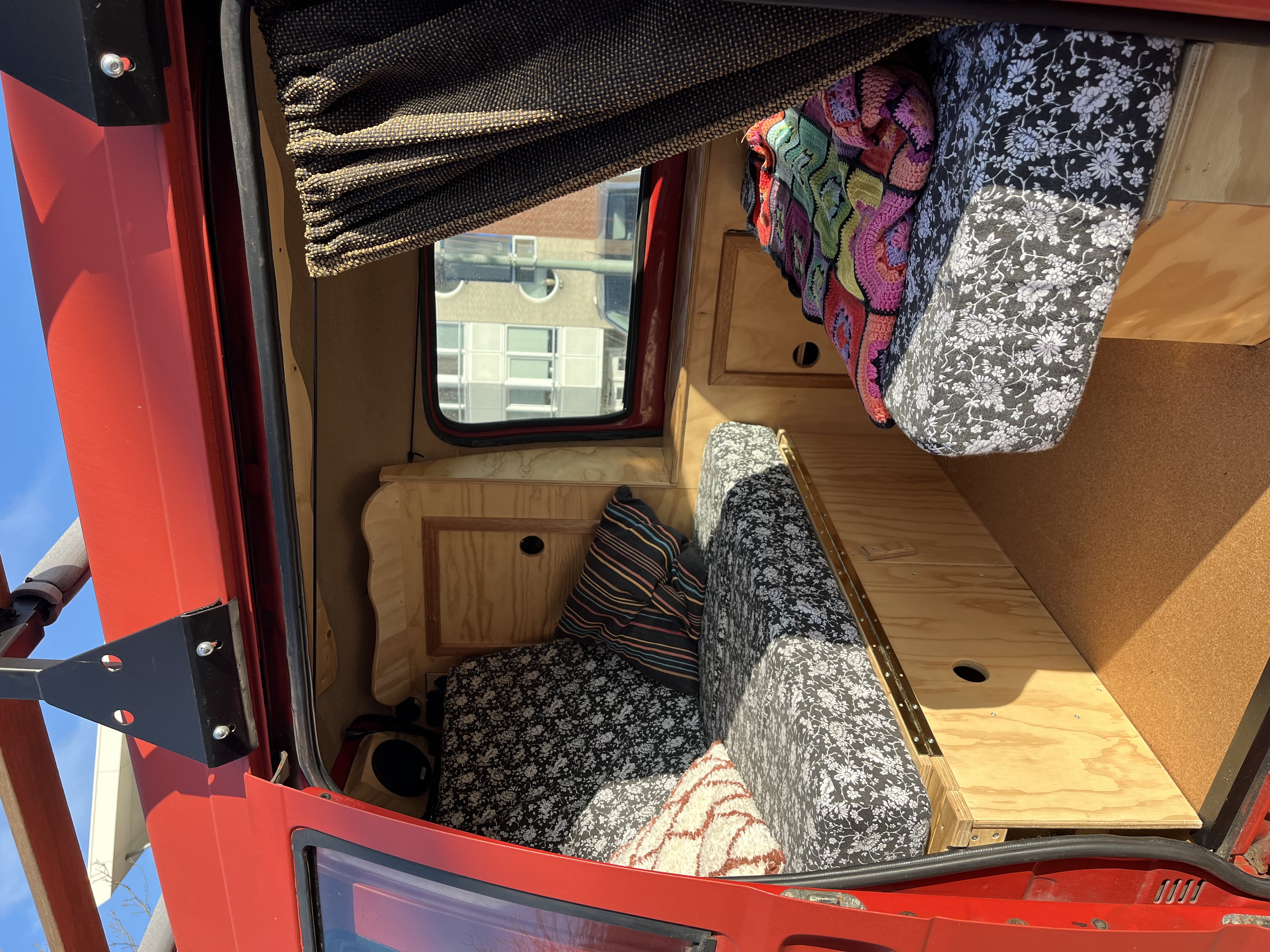 Interieur rode Daihatsu: twee zitbanken met bloemenprint bekleding en houten vloer