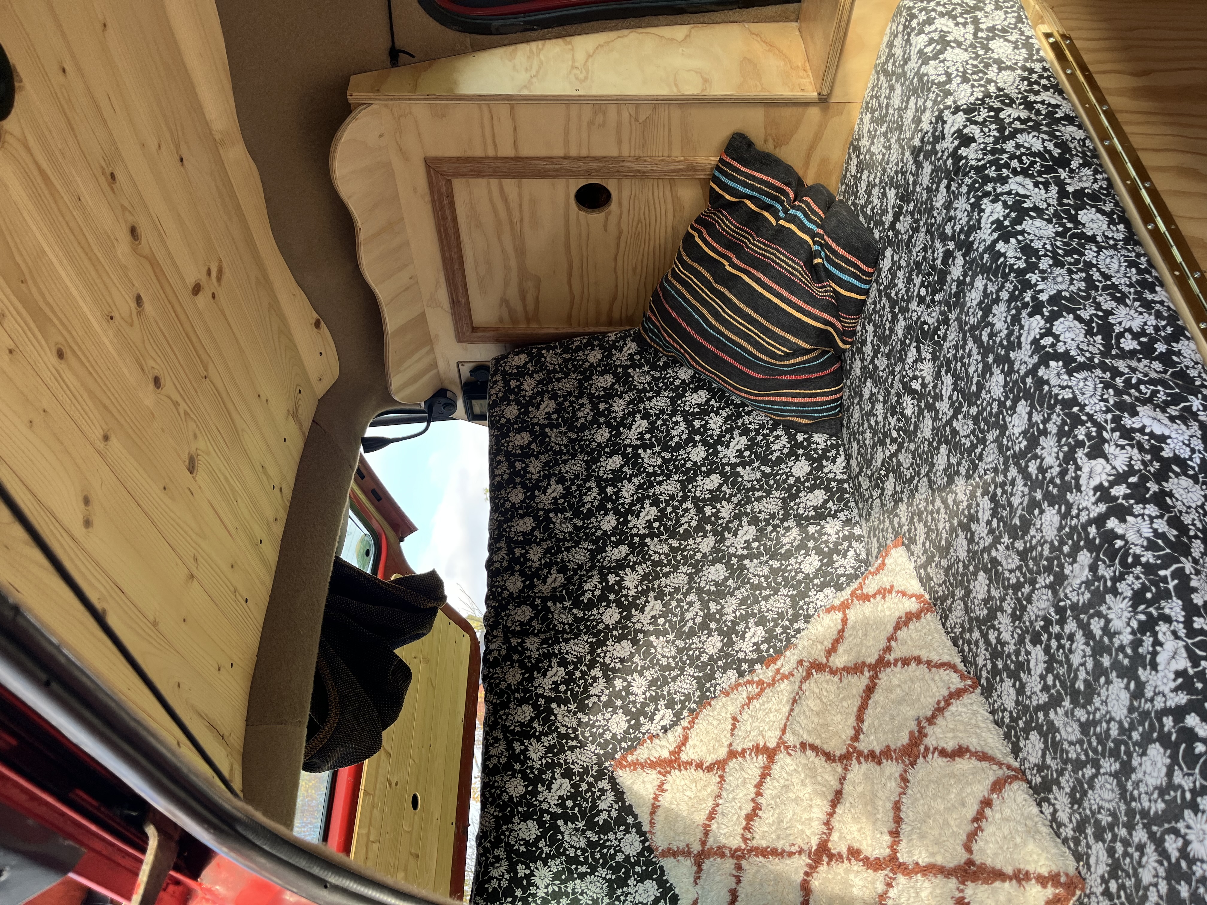 Zitbank met bloemenprint bekleding en kussens in rode bus, houten plafond